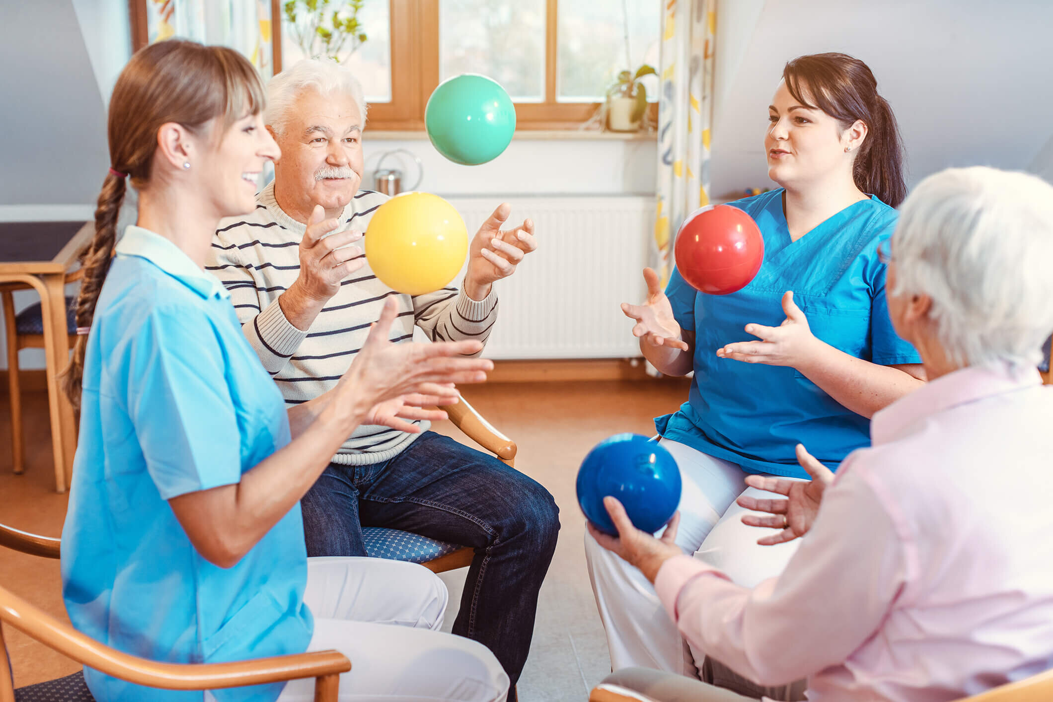 Caregivers and residents tossing coloured exercise balls